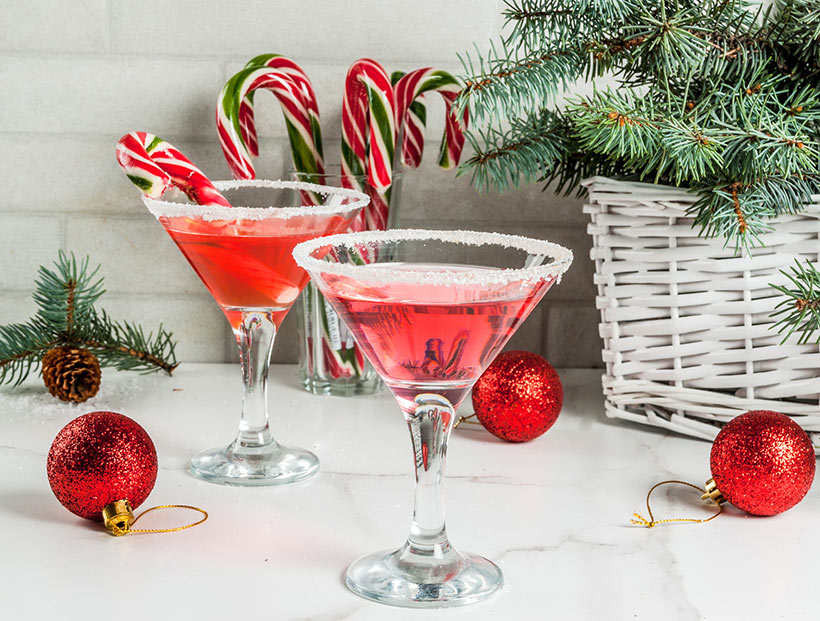 red peppermint martini with festive candy cane garnish and Christmas decorations - vegan Christmas recipes