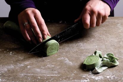 slicing the roll of pasta dough into thin spirals