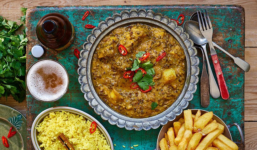 Lentil curry served with chips and a pint of vegan beer 