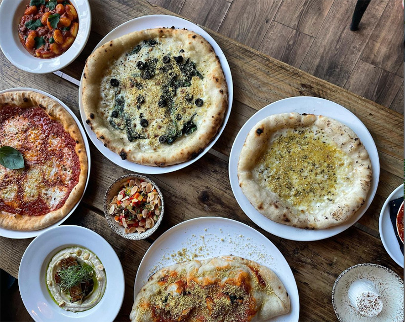 Pizza and other meals arranged on wooden table