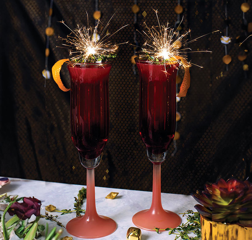 deep red sloe royale cocktail in champagne flutes with sparklers