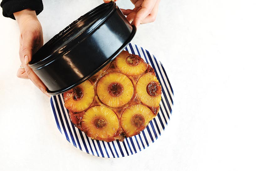 vegan pineapple upside down cake presented on plate with tin being lifted off