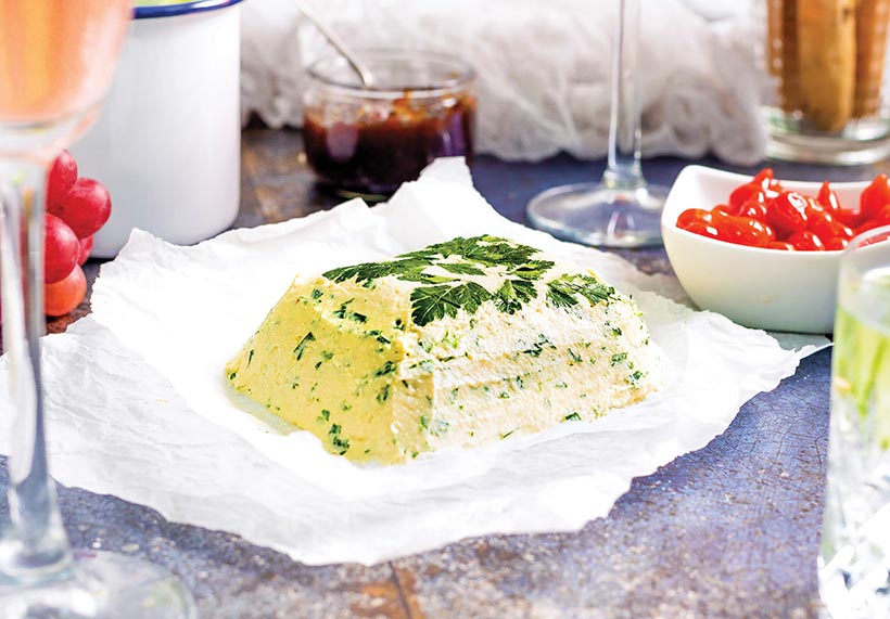 Vegan Boursin cheese served on paper with glasses of wine