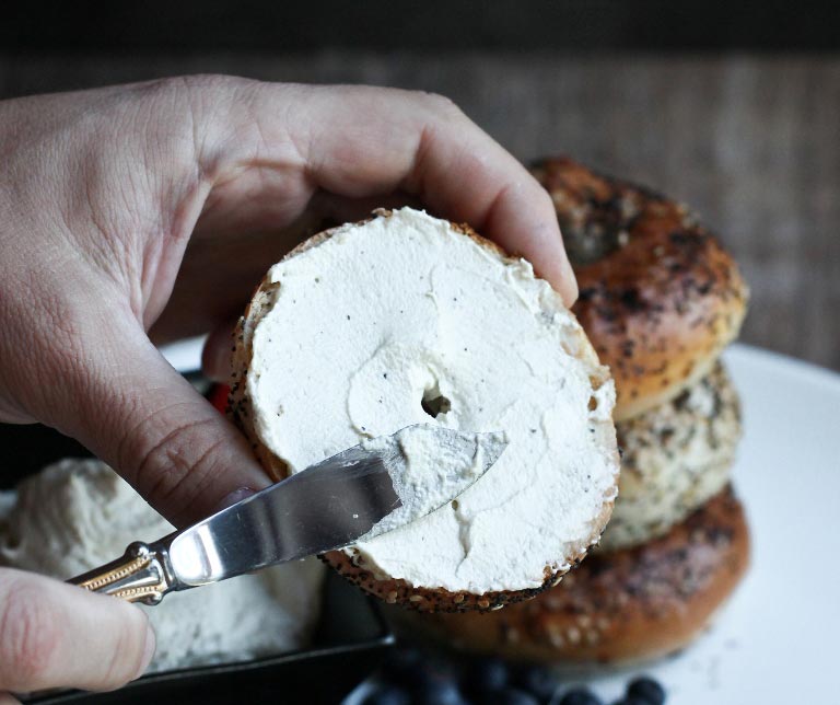 Spreading vegan cream cheese on a bagel